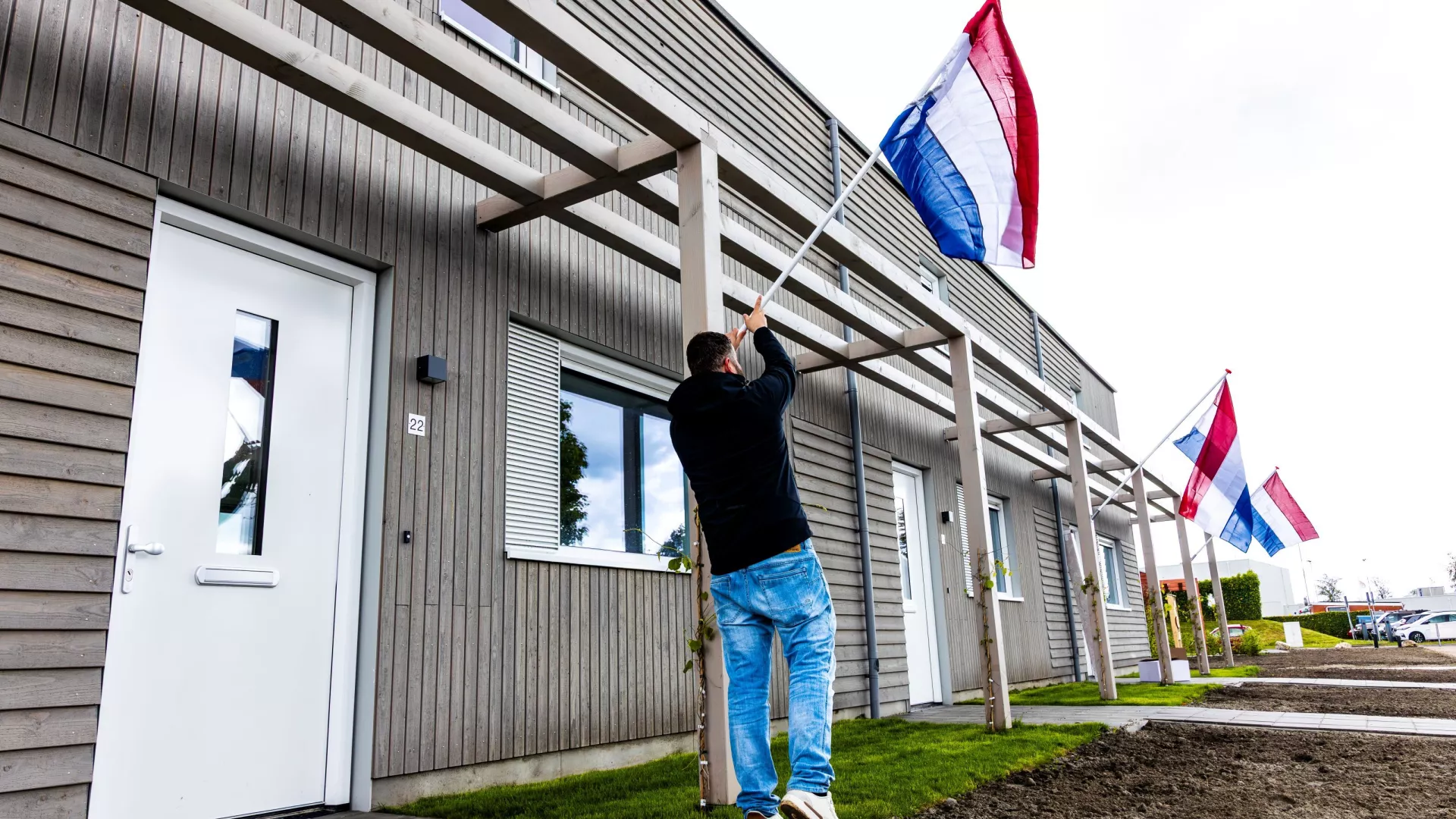 Projectconsulent hangt vlaggen aan de gevel van nieuwe woningen Zuiderstraat