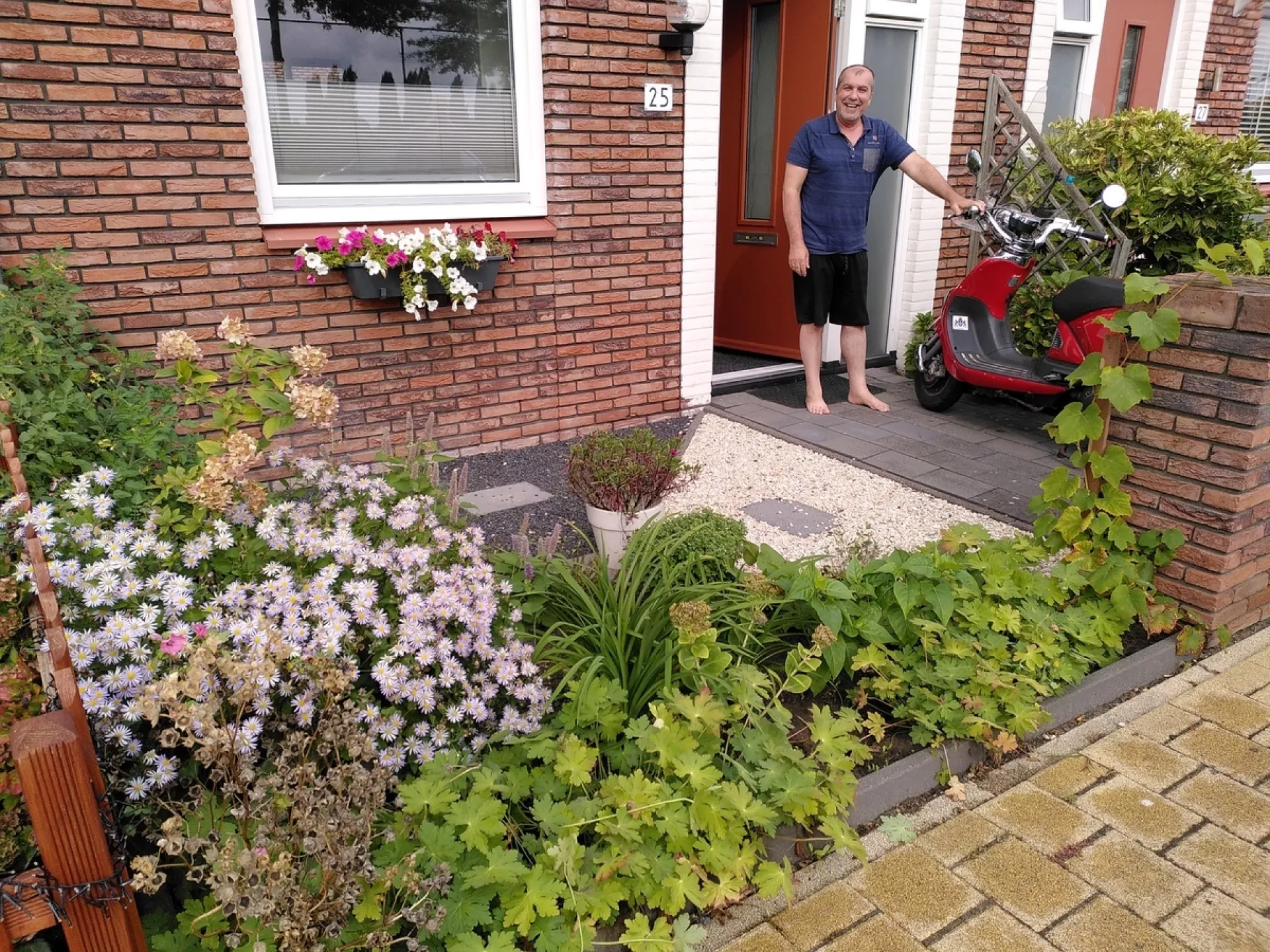 Huurder staat in voortuin met groenstrook